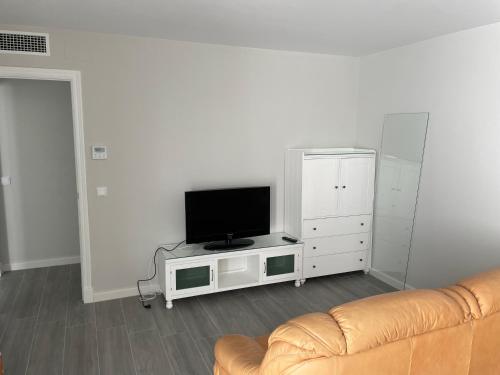een woonkamer met een bank en een flatscreen-tv bij Nuevo Azorin I in Conil de la Frontera