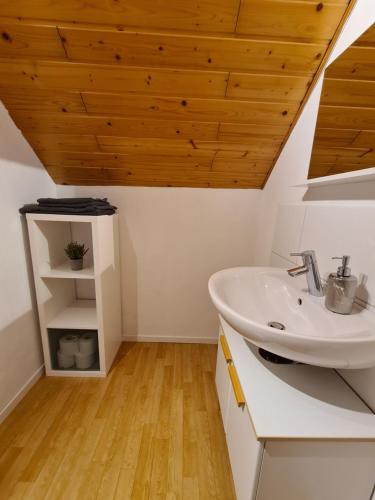 a bathroom with a sink and a wooden ceiling at Pensionszimmer Larifari in Drees