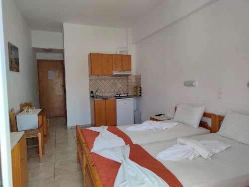 two beds in a room with a kitchen at Sofia Studios & Apartments in Georgioupolis