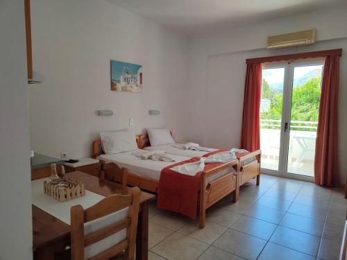 a bedroom with two beds and a sliding glass door at Sofia Studios & Apartments in Georgioupolis