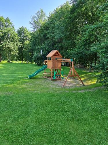 a playground with a slide and a play house at Atostogų namelis-pirtis Prie upės in Anykščiai