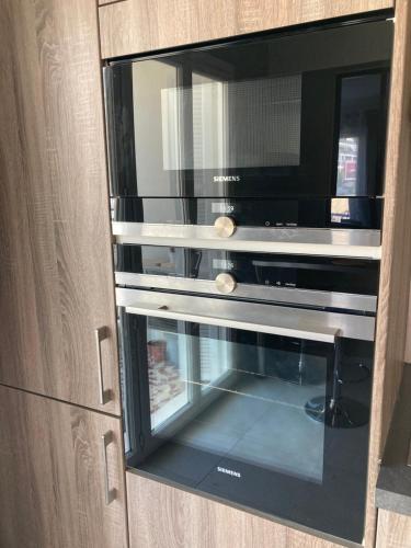 a microwave oven sitting inside of a wooden cabinet at Nice west cosy flat balcony, near airport, train, beach, public transport, supermarket, comfortable and well equipped in Nice
