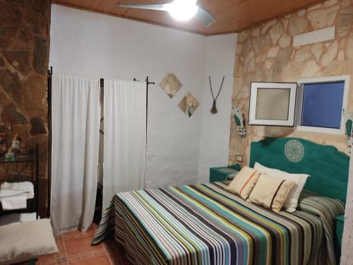 1 dormitorio con 1 cama con una manta a rayas de colores en Rincón de Morote, en Molinicos