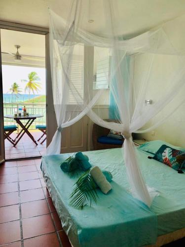 1 dormitorio con cama con dosel y vistas al océano en LeLagon Vue Mer, Pieds dans l'eau, en Saint-François