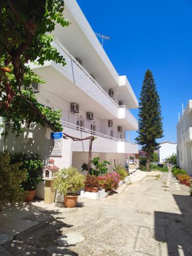 a large white building with a tree in front of it at Sofia Studios & Apartments in Georgioupolis