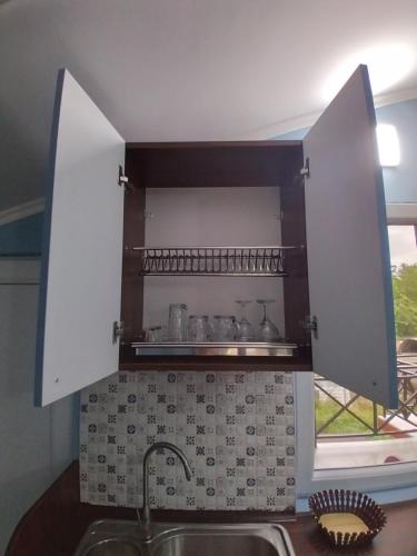 a kitchen with a sink and a shelf with pots and pans at Апарт-отель "У речки" in Kuchkisabano