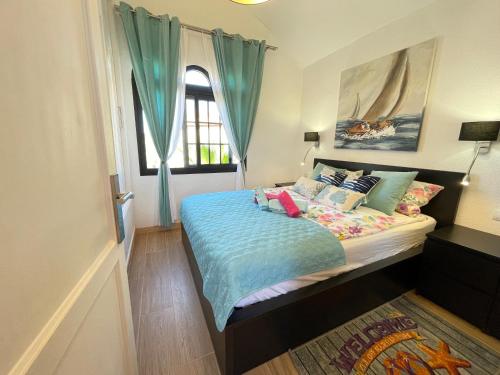 1 dormitorio con 1 cama con sábanas y almohadas azules en AGPI Fuerteventura Apartments Internet Fibra WIFI GRATIS, en Costa Calma