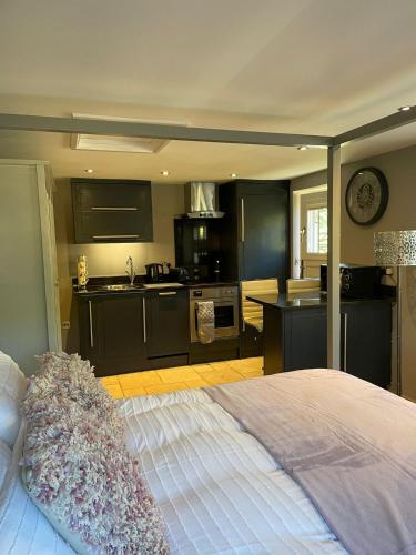 a bedroom with a large bed and a kitchen at Honeysuckle Cottage - Hillside Holiday Cottages, Cotswolds in Warmington