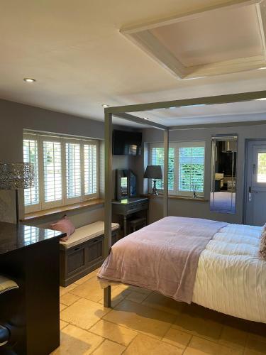 a bedroom with a bed and a desk and windows at Honeysuckle Cottage - Hillside Holiday Cottages, Cotswolds in Warmington
