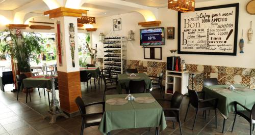 un restaurante con mesas verdes, sillas y TV en Hotel-Restaurante Ancora, en Puerto López