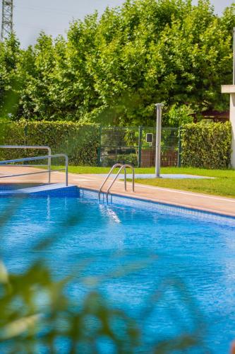 a swimming pool with blue water and metal rails at Camping Cambrils Caban in Cambrils