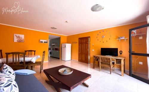 ein Wohnzimmer mit orangefarbenen Wänden und einem Tisch in der Unterkunft B-Rent Mariposa Private Garden in Corralejo