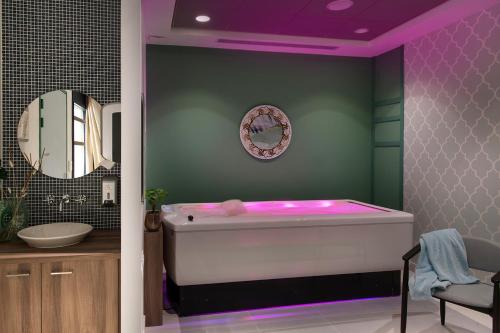 uma casa de banho com banheira e iluminação roxa em Résidence services seniors DOMITYS LES EAUX VIVES em Digne-Les-Bains