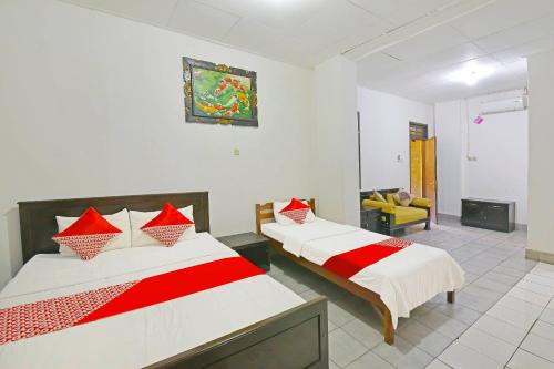 um quarto com 2 camas com lençóis vermelhos e brancos em OYO 3244 Grand Chandra Hotel em Denpasar