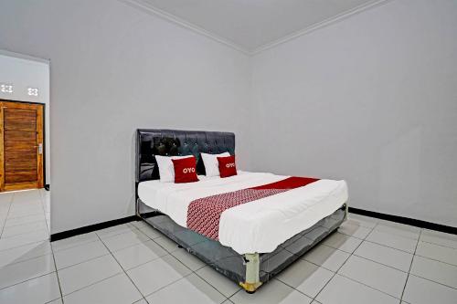 ein Schlafzimmer mit einem großen Bett mit roten Kissen in der Unterkunft OYO 91334 Permata Papua Guest House in Pameungpeuk