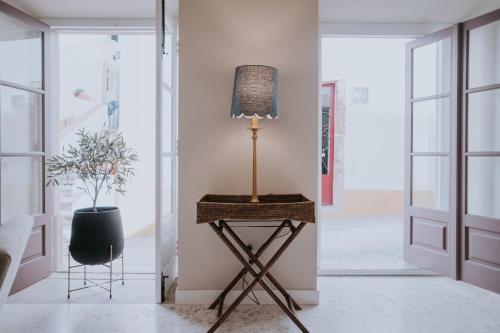 a lamp on a stand in a room with a plant at CasadoRioHotel in Constância