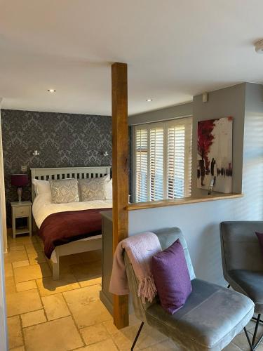 a bedroom with a bed and a chair and a mirror at Lavender Cottage - Hillside Holiday Cottages, Cotswolds in Warmington