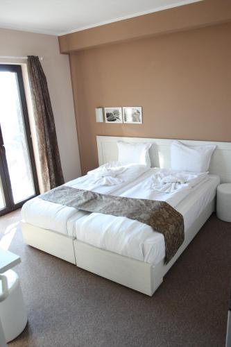a large white bed in a room with a window at Milano Hotel in Burgas