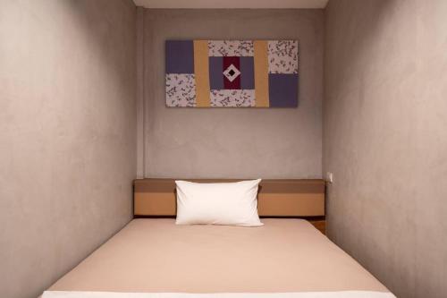 a bed in a small room with a white pillow at Buri Hostel Bangkok in Amphoe Phra Khanong