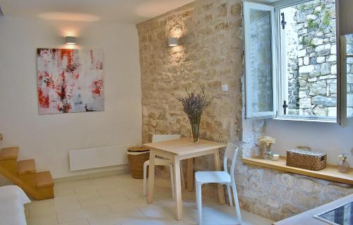 a dining room with a table and chairs and a window at Rooms and Studio Old Town in Rab