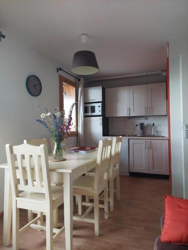 - une cuisine avec une table, des chaises et un vase de fleurs dans l'établissement Before Sunrise 2 Chambres et Parking privé, à Super-Besse