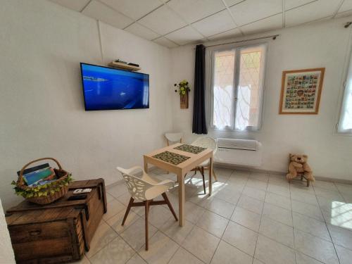 uma sala de estar com uma mesa e uma televisão na parede em Suquet 22 – 2 Pièces, Cannes Cœur Historique, Calme, Plage à 300m, Parking em Cannes