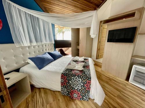 a bedroom with a white bed with blue pillows at Pousada Ponta da Vigia in Penha