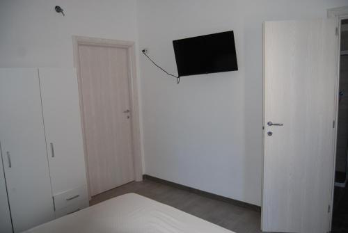 a white bedroom with a tv on the wall at Sognando Positano in Naples