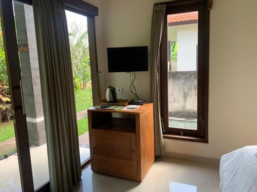 a room with a desk with a television and a window at Wonder-Land Villa in Ubud