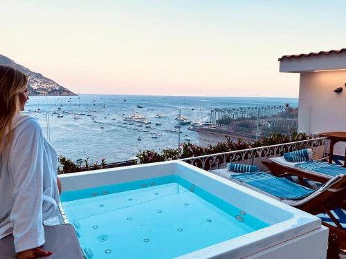 a woman standing on a balcony looking at the ocean at Villa Diamond Luxury Suite in Positano