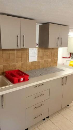a kitchen with white cabinets and a red tray on the counter at Vila Arthur in Eforie Nord