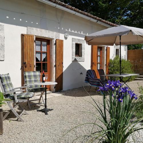a patio with a table and chairs and an umbrella at La Vieille Gorce Gîtes in the Vienne in Asnois