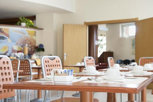 ein Zimmer mit Tischen, Stühlen, Tellern und Küchenutensilien in der Unterkunft Hotel Re in Lissone