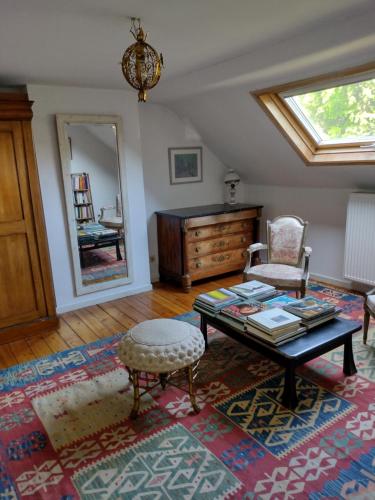 een woonkamer met een tafel, een stoel en een spiegel bij L Heure Bleue in Wezembeek-Oppem