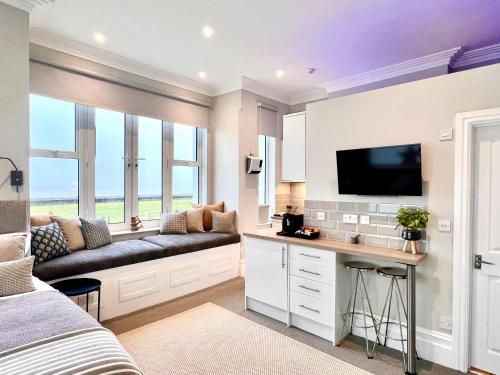 a bedroom with a couch and a tv on a wall at Beachfront Compact Coastal Crib, DIRECT Sea Views & Air Conditioning in Littlestone-on-Sea