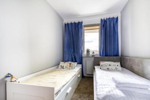 sypialnia z 2 łóżkami i niebieskimi zasłonami w obiekcie Gama Home Wyspowa 1 w Warszawie