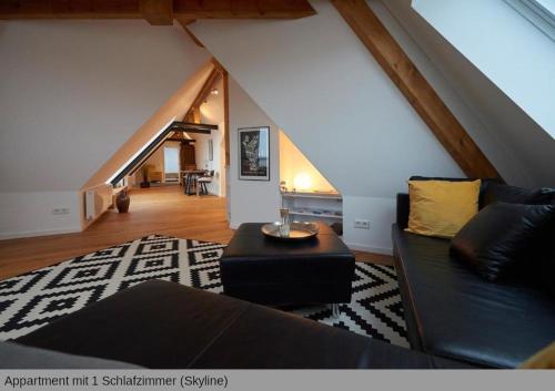 a living room with a black couch and a staircase at Lofts in Hannover in Hannover