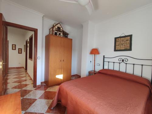 1 dormitorio con cama roja y armario de madera en CASA RURAL FERRETE, en Cañete la Real
