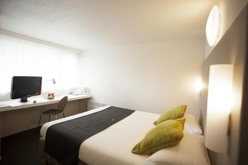 Dormitorio con cama, escritorio y TV en Campanile Pontarlier, en Pontarlier