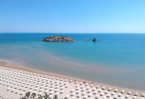 una playa con un montón de sombrillas y el océano en Gattarella Family Resort - Seaside Rooms and Suites with Premium Half-Board à la carte, en Vieste