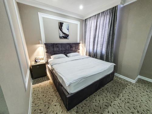 1 dormitorio con 1 cama grande en una habitación en Ritz Hotel en Atyraū