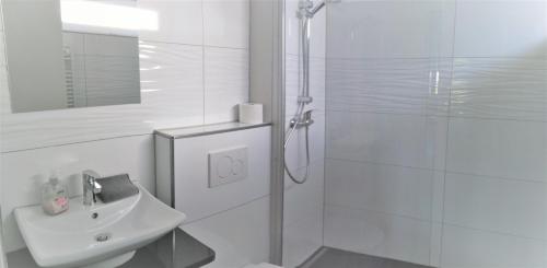 a white bathroom with a shower and a sink at Villa Vogelsang VV, Schwimmbad, Sauna in Sierksdorf