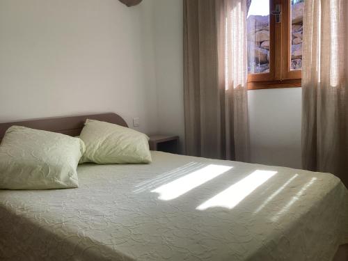 een slaapkamer met een bed waar de zon door een raam schijnt bij Fiori Di Santa Giulia in Porto-Vecchio