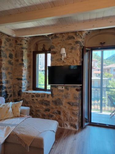 a bedroom with a stone wall with a flat screen tv at Rodanthe's Guest House in Stemnitsa