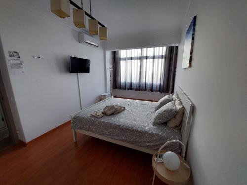 um pequeno quarto com uma cama e uma janela em AL - Comfortable House em Faro