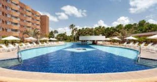 uma grande piscina com cadeiras brancas e um hotel em GRAN LENÇÓIS FLAT - APTO PARTICULAR em Barreirinhas