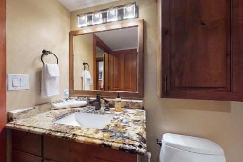 a bathroom with a sink and a toilet and a mirror at Powderhorn Lodge 408: Rustic Mountain Suite in Solitude