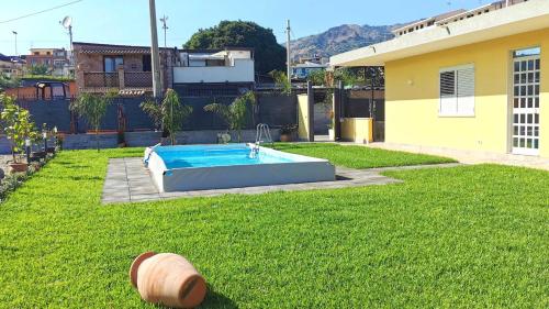 een tuin met een zwembad in het gras bij La Villa Trinacria in Giardini Naxos