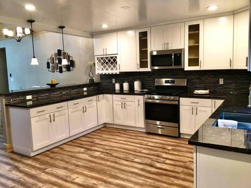 a kitchen with white cabinets and a wooden floor at Modern Cabin Get Away - close to APPLE HILL in Pollock Pines