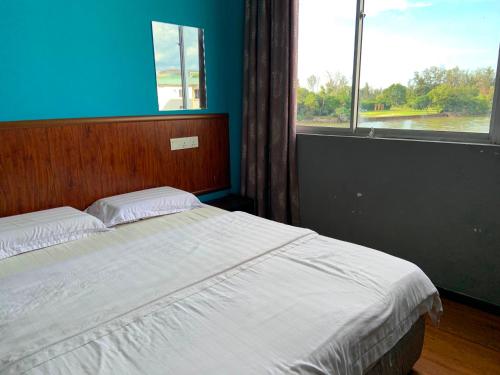 a bedroom with a bed with a blue wall and a window at Super OYO 90579 U Inn in Miri
